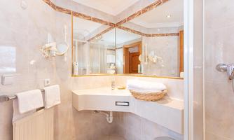 A modern bathroom with a large mirror and bright, friendly design. It is well-lit and offers a clean, inviting atmosphere.
