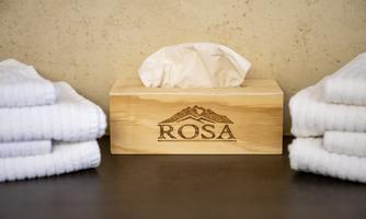 An elegant bathroom setup with a wooden box for tissues and folded towels. The box is engraved with the name "ROSA."