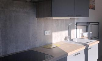 A modern kitchen with dark cabinets and a bright countertop. The kitchen space is well-lit and tidy.