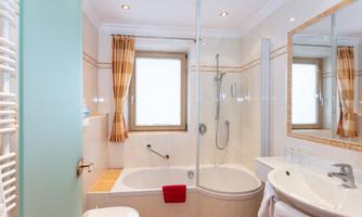 A modern bathroom with a shower and bathtub. Bright walls and large windows create a friendly atmosphere.