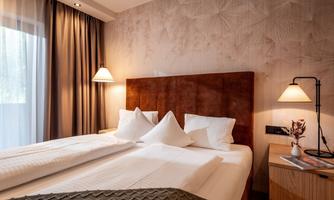 A modern hotel room with two single beds and elegant furnishings. Soft lighting and curtains create a cozy atmosphere.