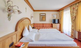 A cozy bedroom with two beds and a sofa. The bright decor and the view through the window create a friendly atmosphere.