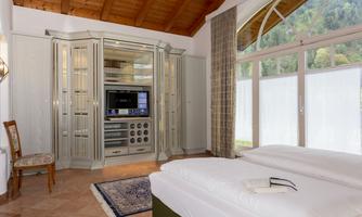 A modern room with a double bed and a large, elegant wardrobe.  
Large windows provide plenty of daylight and a view of nature.
