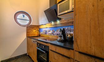 A modern kitchen with wooden furniture and stylish furnishings. The room features a large window and an impressive landscape graphic.
