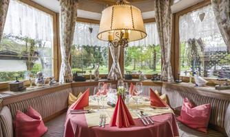 An inviting restaurant with a beautifully set table. Large windows offer a view of the outdoor area.