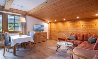 A cozy living space with wooden details and floor-to-ceiling windows. The room is brightly lit and invites relaxation.