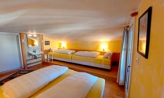 A cozy room with two single beds and a warm yellow paint. The light creates an inviting atmosphere.