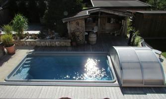 A beautiful garden with a pool and a canopy. In the background, you can see a cozy wooden gazebo and numerous plants.