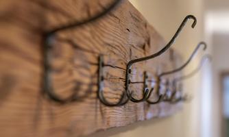 A wooden strip with several hooks, ideal for storing jackets or accessories. The hooks are made of black metal and give a rustic look.