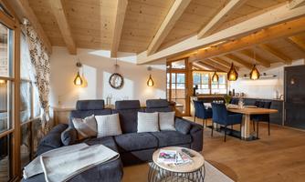 A modern living room with wooden ceilings and cozy furnishings. The room is bright and inviting, perfect for relaxed moments.
