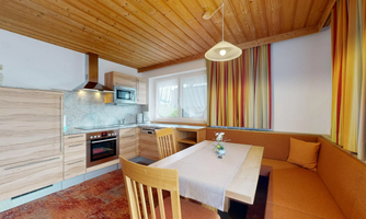 A modern kitchen with wood decor and a dining table. The warm colors and the cozy atmosphere invite you to linger.