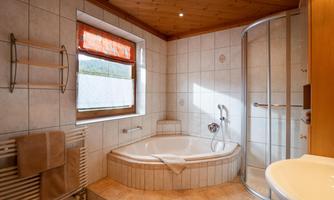 A modern bathroom with a round bathtub and a shower cubicle. Large windows provide plenty of natural light.