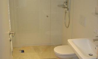 A modern bathroom with a walk-in shower and a sink. A colorful bath mat is on the floor.