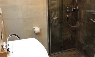 A modern bathroom with a shower and a sink. The walls are painted in neutral tones, creating a relaxed atmosphere.