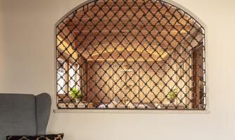 A beautiful room with a decorative arch-shaped grid. Plants are visible over the grid, creating an inviting atmosphere.