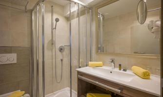 A modern bathroom with a second shower and a sink. Yellow towels are neatly arranged.