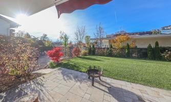 A beautiful garden with well-kept grass and colorful plants. The sun is shining and the sky is clear.