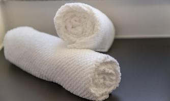 Two neatly rolled white towels lie on a dark surface. They appear fresh and inviting.