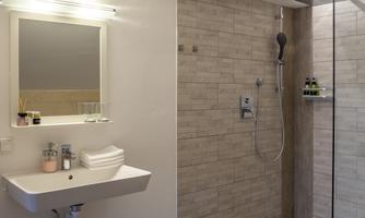 A modern bathroom with a sink and a large shower area. The walls are adorned with bright tiles and there is a mirror above the sink.