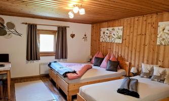 A cozy bedroom with two beds and wood paneling. Soft colors and decorations create an inviting atmosphere.