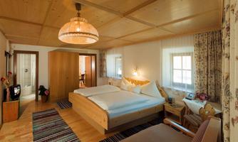A cozy bedroom with a large double bed and wooden furniture.  
Soft lighting and a pleasant ambiance invite you to relax.
