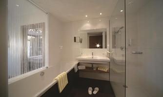 A modern bathroom with a bathtub and a shower. Bright walls and soft lighting create an inviting atmosphere.