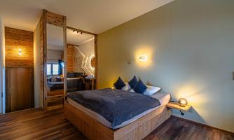 A cozy bedroom with a large wooden bed and modern accents. The warm colors and wood create an inviting atmosphere.