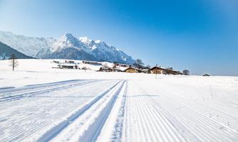 A winter landscape with fresh snow and mountains in the background. Clear blue skies and well-groomed ski slopes give the scene a tranquil mood.