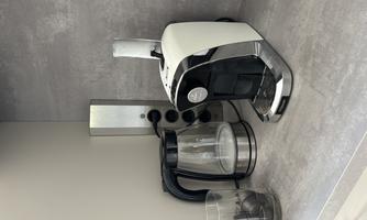 A modern kitchen corner with a white coffee machine and a glass carafe. The appliances are on a gray countertop.