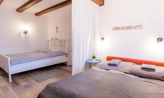 A cozy bedroom with two beds and bright walls. The room is modern and inviting, with wooden details and soft lighting.