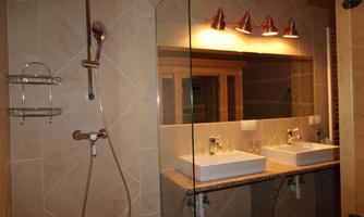 A modern bathroom with two sinks and a shower. The space is bright and elegant with high-quality fixtures.
