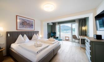 A cozy hotel room with two beds and modern furniture. Large windows offer a view of the countryside.