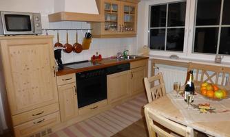A cozy kitchen with wooden cabinets and modern appliances. The table is set with fruit and a glass of champagne.