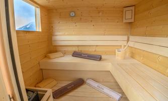 A cozy sauna with light wood paneling and benches. A window provides a view outside.