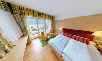 A cozy hotel room with two beds and a beautiful view of the lake. The windows let in plenty of light and the room is pleasantly furnished.