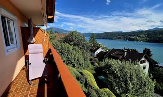 A beautiful view from a balcony of a lake and the surrounding mountains. The landscape is green and inviting, ideal for relaxation and recreation.