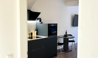 A modern kitchen view with hardwood flooring and simple furniture. The room is bright and inviting.