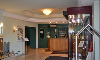 A bright hotel lobby with a reception desk and modern furniture. The space is designed to be friendly and inviting.