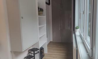 A bright hallway with a white shelf and a coat rack. Flowers and lanterns are placed on the floor.