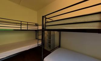 A simple bedroom with two bunk beds and a neutral wall color. The room is bright and tidy.