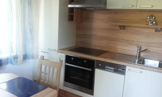 A modern kitchen with wooden and white elements. The table has blue placemats and there is a stainless steel sink as well as a stove.