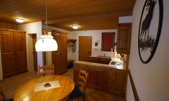 A cozy kitchen with wooden cabinets and a round table. The warm tones create an inviting atmosphere.