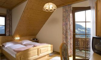 A cozy bedroom with wooden furniture and a large window. The room offers a view of the mountains and has an inviting atmosphere.
