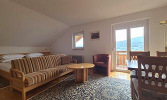 A cozy room with a sofa, a table, and a chair. Large windows offer a view of the mountains.