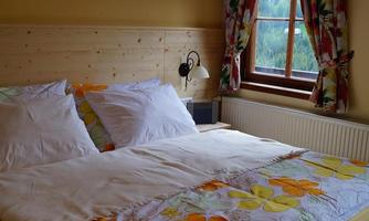 A cozy bedroom with a double bed and colorful bedding. Large windows and colorful curtains create a bright and inviting atmosphere.