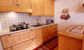 A cozy kitchen with wooden furniture and modern amenities. On the countertop are pots and a microwave.