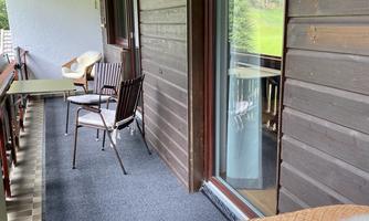 A cozy balcony with a view of the green surroundings. There are chairs and a table for relaxing hours outdoors.