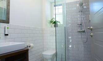 A modern bathroom with a glass shower and a stylish tiled floor. A large window ensures plenty of daylight.