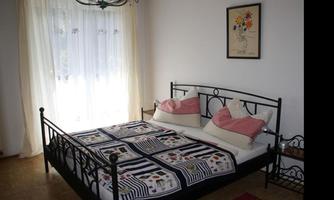 A cozy bedroom with a double bed and colorful cushions. 

Light-flooded windows create an inviting atmosphere.