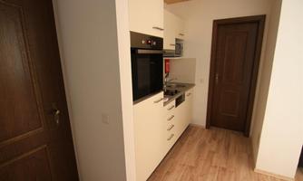 A modern kitchen with bright cabinets and wooden floors. The equipment includes an oven, stove, and sink.